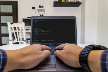 Uzaktan kumanda merkezi. Evdeki bir dizüstü bilgisayarda kod yazan bir programcının düşük açılı görüntüsü.