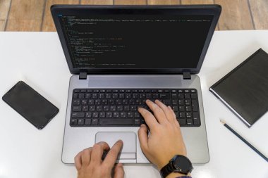 Ev kavramından çalış. Dizüstü bilgisayarda kod yazan bir programcının görünümünün üstünde.