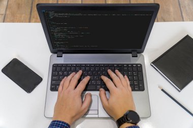 Ev kavramından çalış. Dizüstü bilgisayarda kod yazan bir programcının görünümünün üstünde.