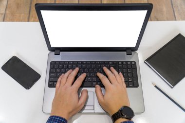 Merkez ofis konsepti. Masada boş bir ekranla dizüstü bilgisayarda yazan kişinin üst görünümü.