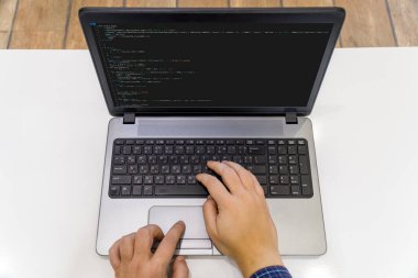 Ev kavramından çalış. Dizüstü bilgisayarda kod yazan bir programcının görünümünün üstünde.