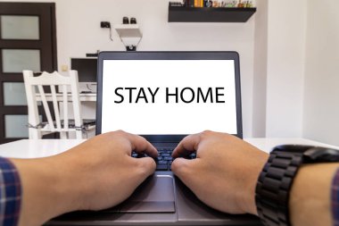 Bilgisayarda çalışan bir kişinin ekranda evde kalma mesajı ile düşük açılı görüntüsü