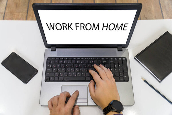 Вид сверху на человека, работающего на ноутбуке с работой из домашнего сообщения на экране
