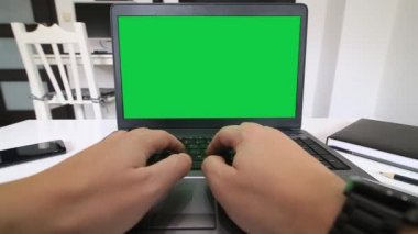 Uzaktan kumanda merkezi. Yeşil ekranlı bir dizüstü bilgisayarda yazan bir programcının düşük açılı görünümü.