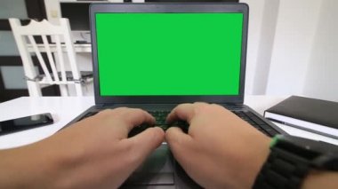 Uzaktan kumanda merkezi. Yeşil ekranlı bir dizüstü bilgisayarda yazan bir programcının düşük açılı görünümü.