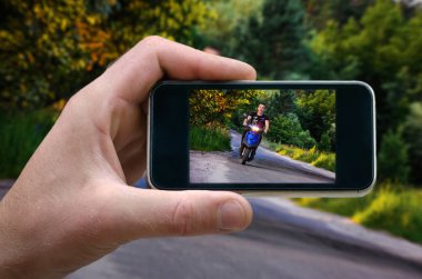 motosikletçi ile karayolu üzerinde bir hızda gidiyor. telefonunuzdan, manzara fotoğraf çekim adam elinde telefon telefonda çekim öz,