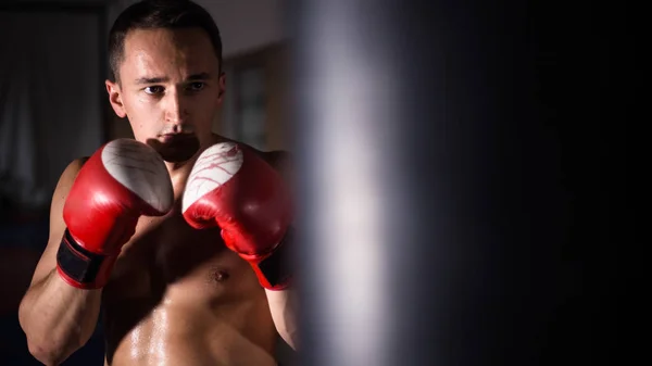 Boxeador musculoso fuerte con guantes de boxeo rojos. Un hombre en un puesto de boxeo. entrenamiento de boxeo —  Fotos de Stock