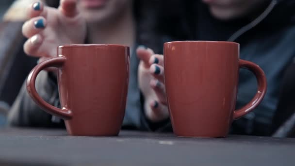 Menina aquece as mãos sobre xícara de bebida quente. casal apaixonado beber café quente — Vídeo de Stock