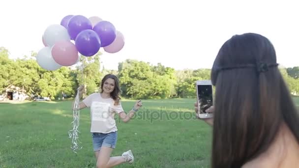 Žena fotografování radostné přítelkyně s balónky — Stock video