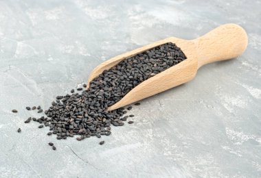 Ahşap kepçe içinde açık beton bir arka planda siyah susam