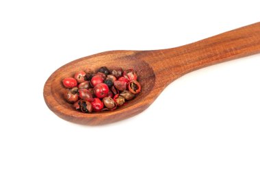 Ahşap kaşıkta kırmızı biberli bezelyeler beyaz arka planda kapanıyor.