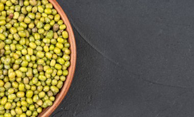 Koyu arkaplanda yeşil fasulyeli bir kasenin parçası.