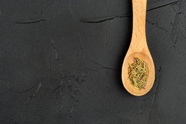 Koyu arka plan üzerinde kuru biberiye yakın çekim ile küçük ahşap kaşık