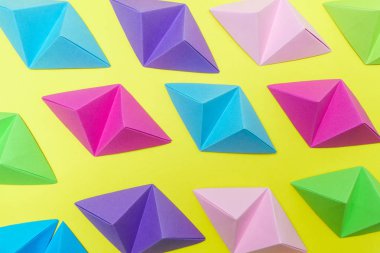 Origami tetrahedrons sarı arka plan üzerinde değişken soyut kompozisyon renkler