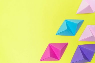 Değişken renkli origami tetrahedrons sarı arka plan üzerinde kopya alanı sol tarafında ile.