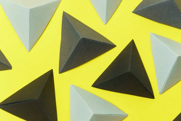 Vista superior de tetraedros de origami gris y negro sobre fondo amarillo . — Foto de Stock