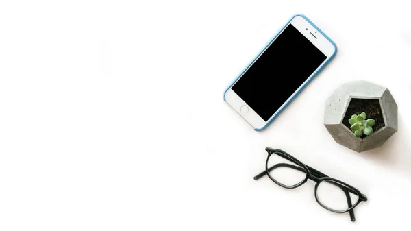 Smartphone, occhiali, pianta ufficio vista dall'alto composizione laica piatta con spazio libero copia sul lato sinistro . — Foto Stock