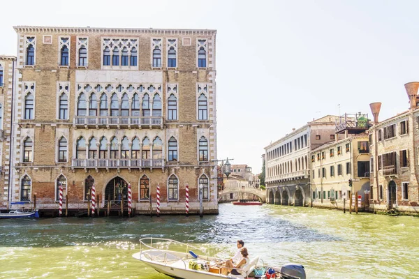 Brilhante edifício veneziano e barco com um casal flutuando entre Grand canal . — Fotografia de Stock