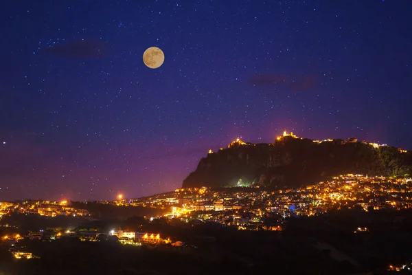 San Marino alla notte di luna piena foto con cielo panoramico e luci brillanti della città di notte . — Foto Stock