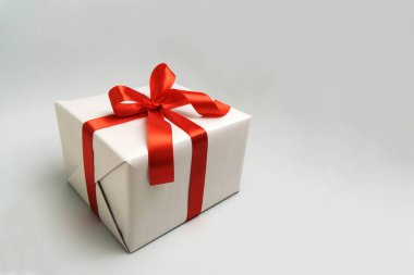 Beyaz hediye kutusu üzerine kırmızı kurdele ile.