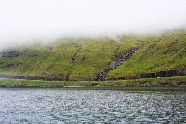 Zielone Wybrzeże Wodospadem Schodzącym Morza Gęstą Mgłą Powyżej Vagar Wyspy — Zdjęcie stockowe