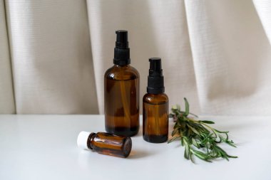 Aromaterapi ve doğal sağlık kavramsal fotoğrafı, cam şişeler dolusu gerekli yağlar ve biberiye bitkisi ile birlikte..