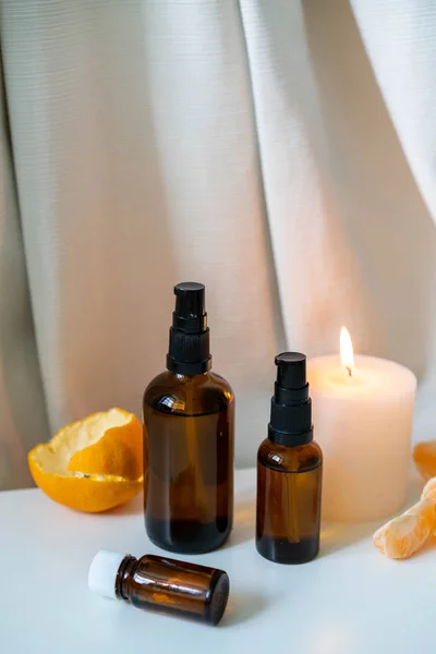 新鮮な柑橘類と白のドレープリーの背景に白いキャンドルとガラス瓶にエッセンシャルオイル アロマセラピーのコンセプト写真垂直方向 — ストック写真