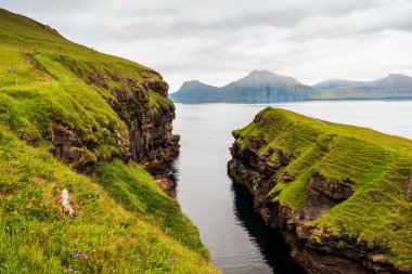 Ufukta Kalsoy adasıyla birlikte Gjogv balıkçı köyünün fiyordu görülüyor. Faroe Adaları, Danimarka.