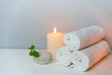 Spa ve doğal sağlık konsepti fotoğrafı. Beyaz havlular, deniz tuzu ve mum ışıkları..