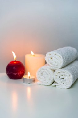 Spa konseptindeki doğal sağlık fotoğrafı, dikey yönelim. Beyaz havlular ve mum ışıkları..