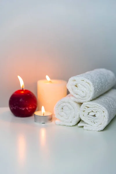 Natural health in SPA concept photo, vertical orientation. White towels and candle lights.