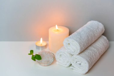 Beyaz havlular, mumlar ve bir fincan deniz tuzu ile gri arka planda güzellik salonu konsepti fotoğrafında spa prosedürü.