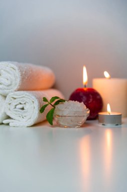 Doğal sağlık ve kaplıca tedavileri dikey fotoğraf. Beyaz havlular, deniz tuzu, mumlar..