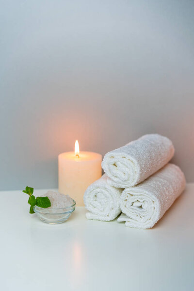 SPA procedures concept photo with candle light, sea salt and stack of towels.