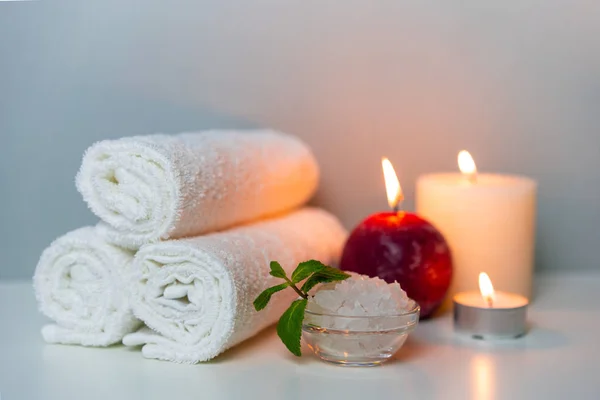 Natural health treatments of SPA. White towels, sea salt in a cup, candles.