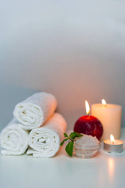 SPA&Massage concept photo with candle lights and stack of white towels, vertical orientation.