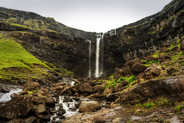 Biggest waterfall of Faroe Islands, Fossa waterfall. Panoramic photo with waterfall stream and green hills.