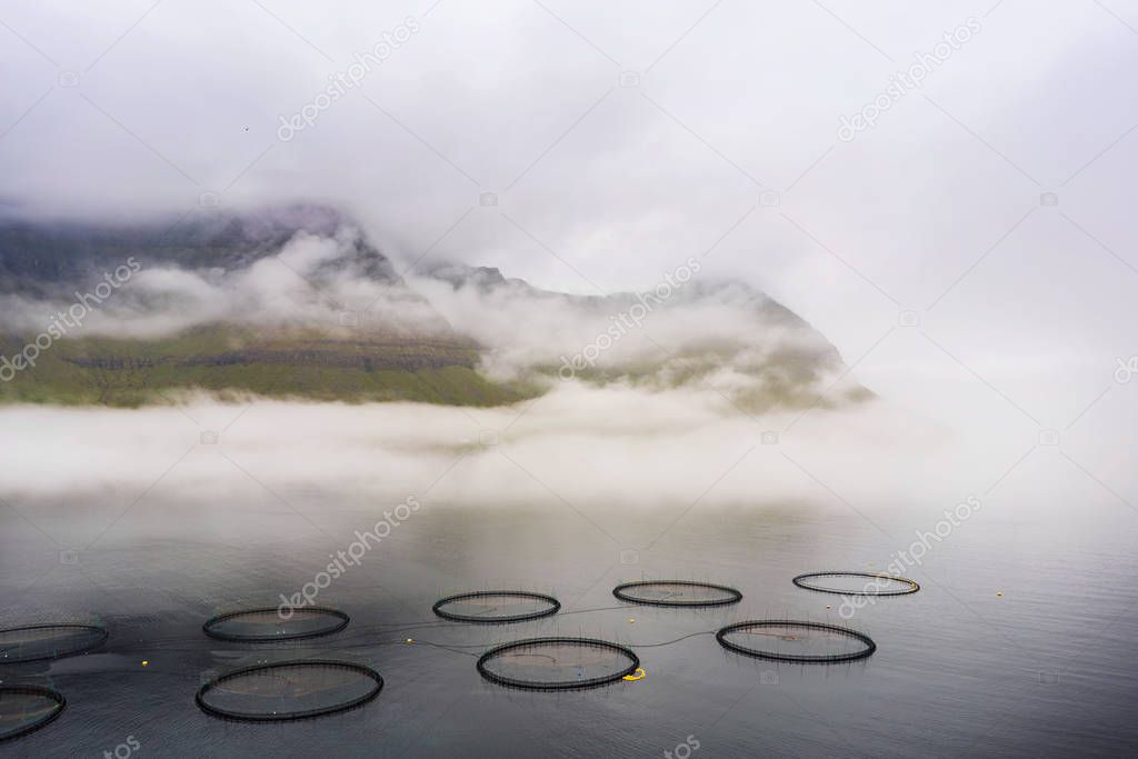 Fish farms on Faroe Islands with outstanding mountain landscape on horizon. Faroe Islands, Denmark.