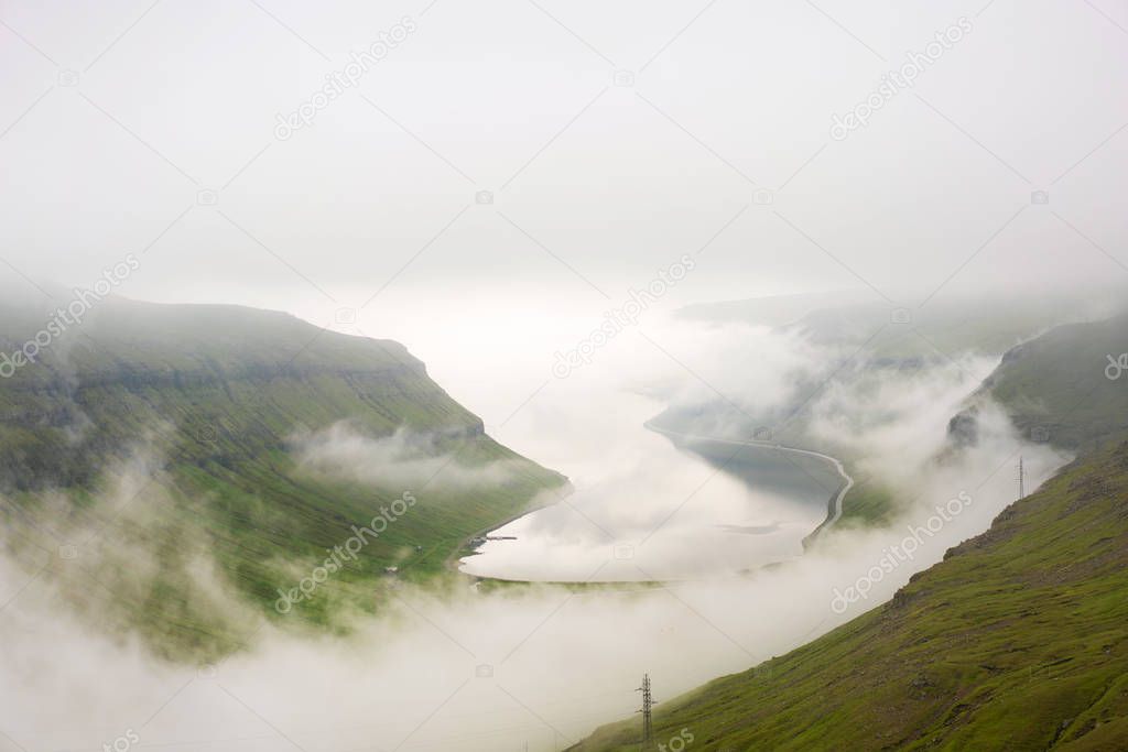 Incredible picture of weather on Faroe Islands in summer with thick fog around a fjord.