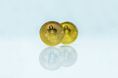 Beyaz yüzeyde yansıması olan altın kripto para birimleri.