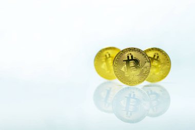 Beyaz yüzeyde yansıması olan bitcoin sikkeleri ve sol taraftaki metniniz için kopyalama alanı.