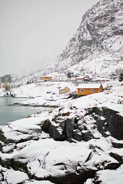 罗浮敦岛上传统的橙色罗浮宫建筑在岩石之上 山上覆盖着积雪和地平线上的大海 — 图库照片