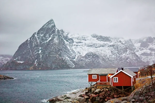 岩石上的红房子 地平线上覆盖着雪的大海和高山 传统的Lofoten家 — 图库照片