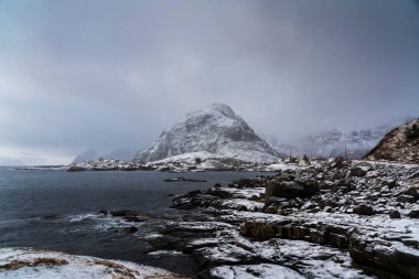 Kutup manzarası, sıradışı bir dağın yakınındaki küçük bir köyün fotoğrafı. Lofoten Adaları, Norveç.