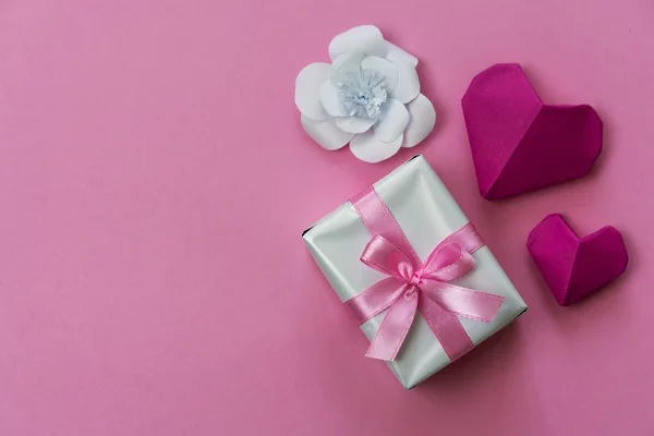 情人节的背景是用粉红缎带 白纸花和折纸心包裹的礼品盒 左边是一个复制的空间 — 图库照片