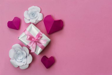 Pembe kurdeleli güzel hediye kutusu, el yapımı kağıt kalpler ve çiçekler, sağda kopyalama alanı.