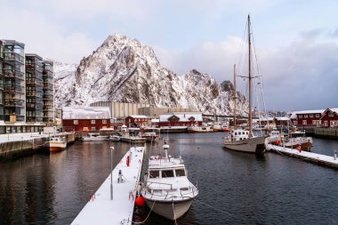 Svolvaer harbor panorama with boats, traditional and modern buildings, Snowy mountain on horizon. Lofoten islands, Norway.