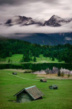 Geroldsee lake during summer rainy day, Bavarian Alps, Bavaria, Germany. Beautiful heavy cloud motion over massive mountains and mows. clipart