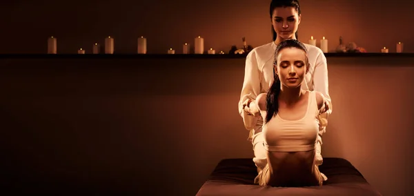 Young pretty woman has Thai massage at luxury spa. Warm inviting colors, calm atmosphere, charming light. — Stock Photo, Image