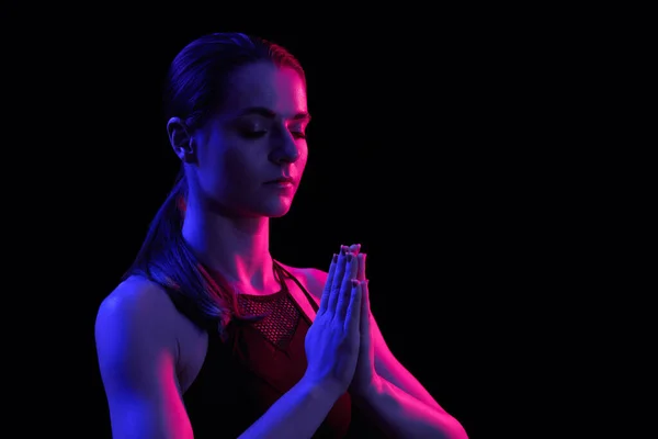 Junge fitte Frau beim Meditieren. Neonlicht. Moderne Science-Fiction-Darstellung von Yoga. Kopierraum. — Stockfoto